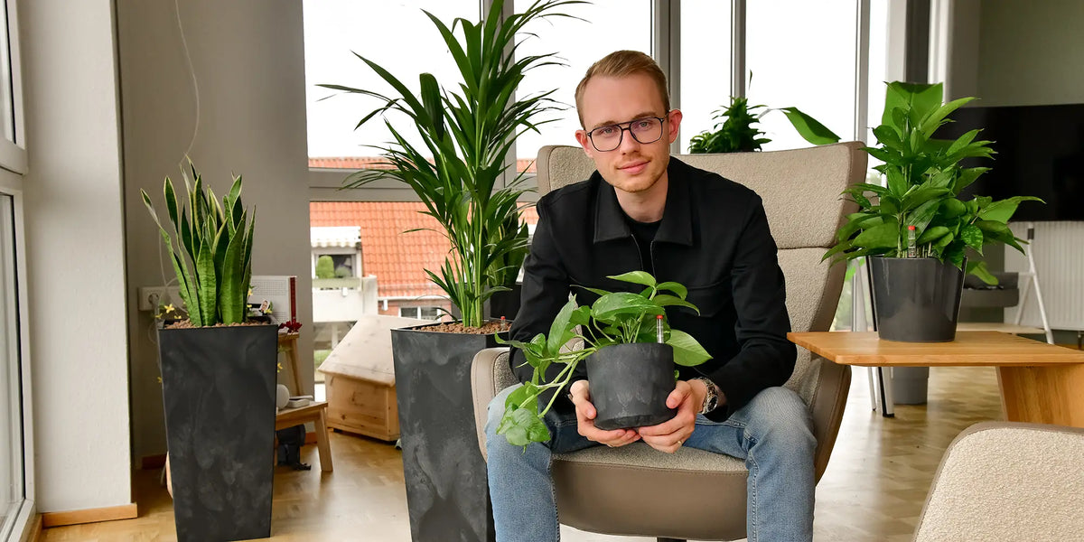 Glücklicher Mann mit Pflanzen in seinem Büro
